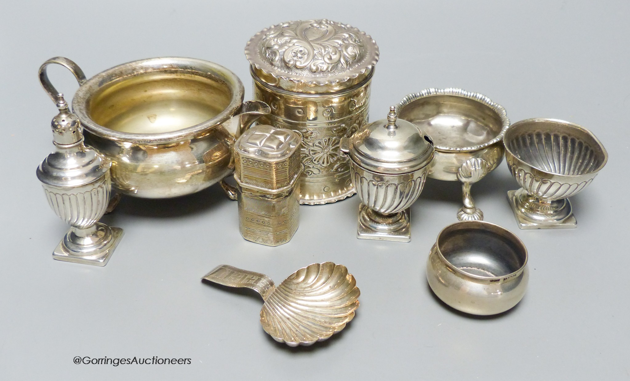 A group of small silver including a late Victorian repousse cannister, three salts, a caddy spoon, two condiments, A small Dutch white metal box and a plated cream jug.